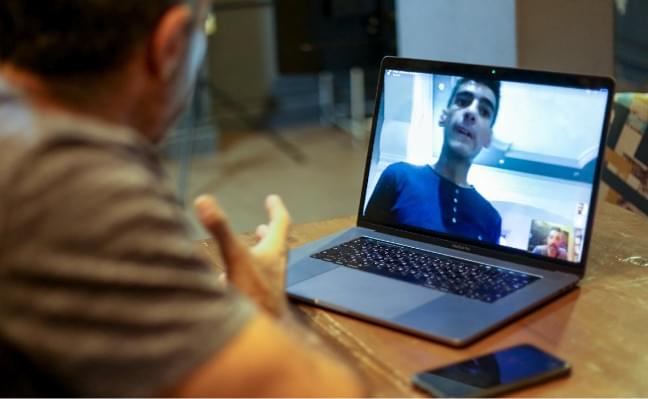 A Syrian man using his laptop for a video call with another man.