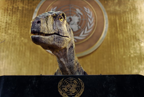 A dinosaur speaks at the podium of the United Nations general assembly hall