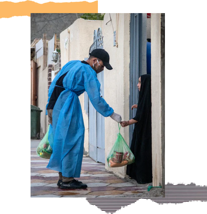 A man in protective gear delivers a bag of food to a young girl